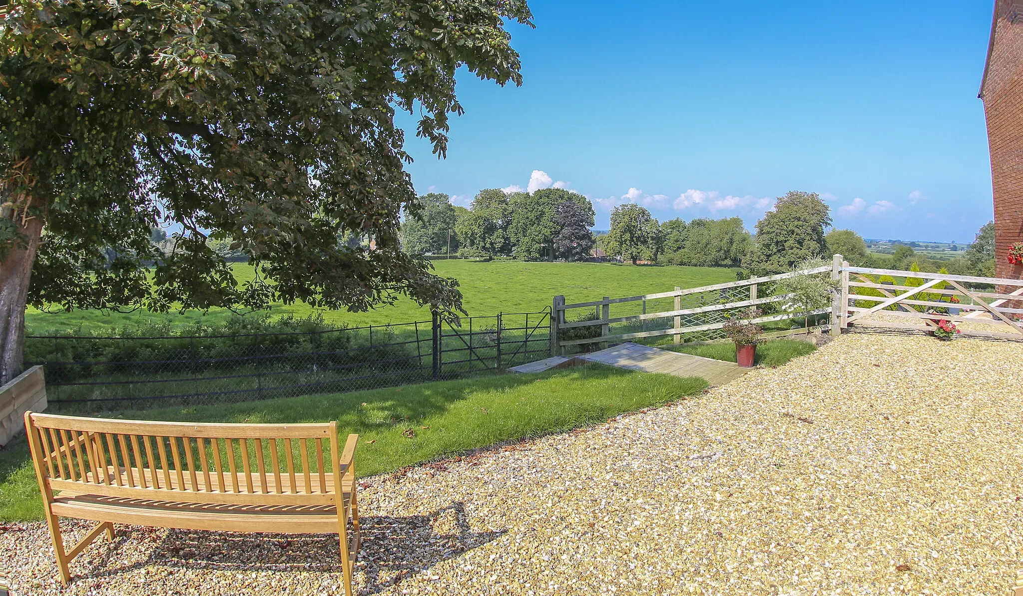Bench on the gravel beside the barns looking out over the fields on a clear summer day