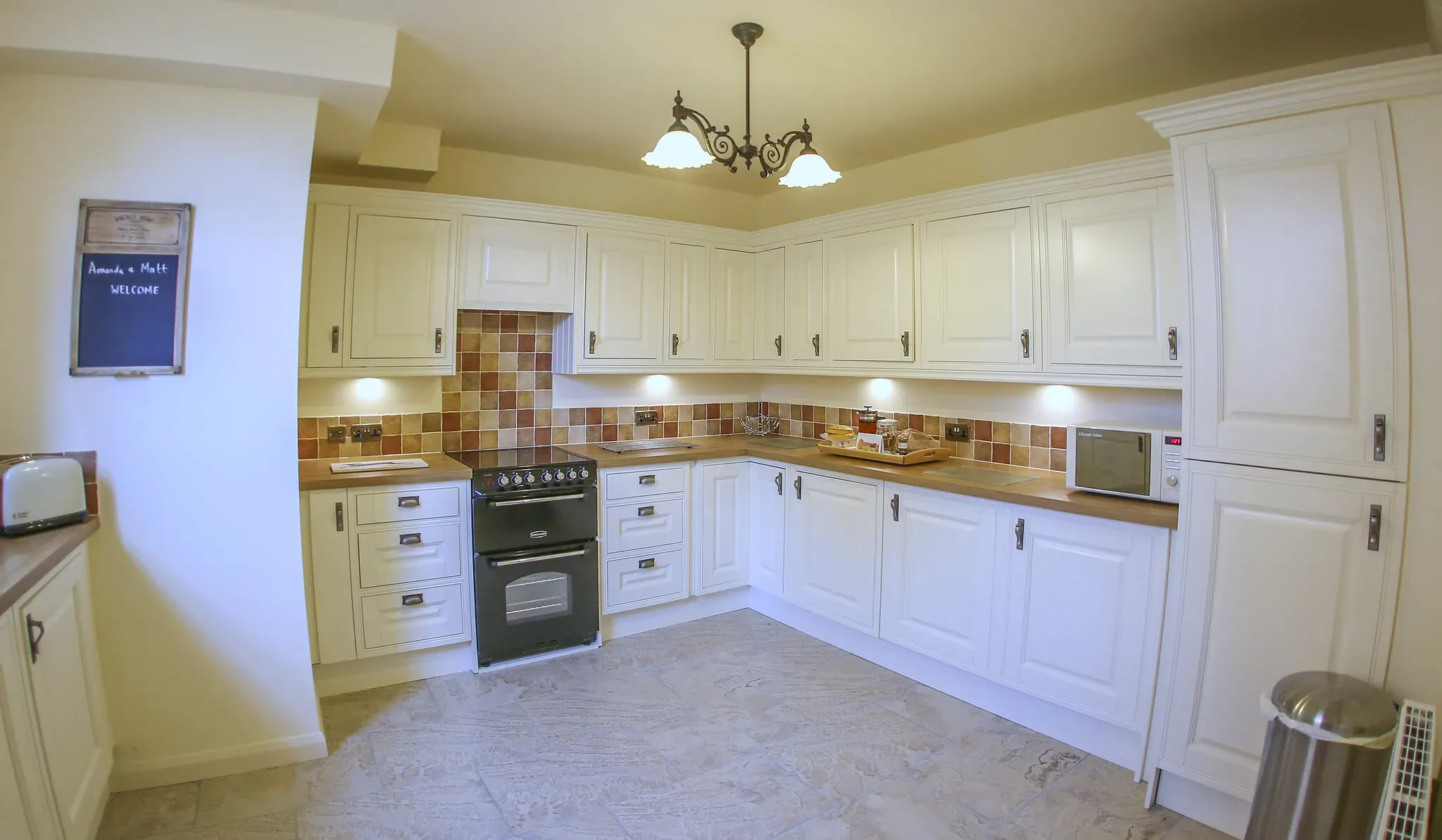 Oak Barn's fully fitted cream kitchen with range cooker and a chalkboard welcome sign