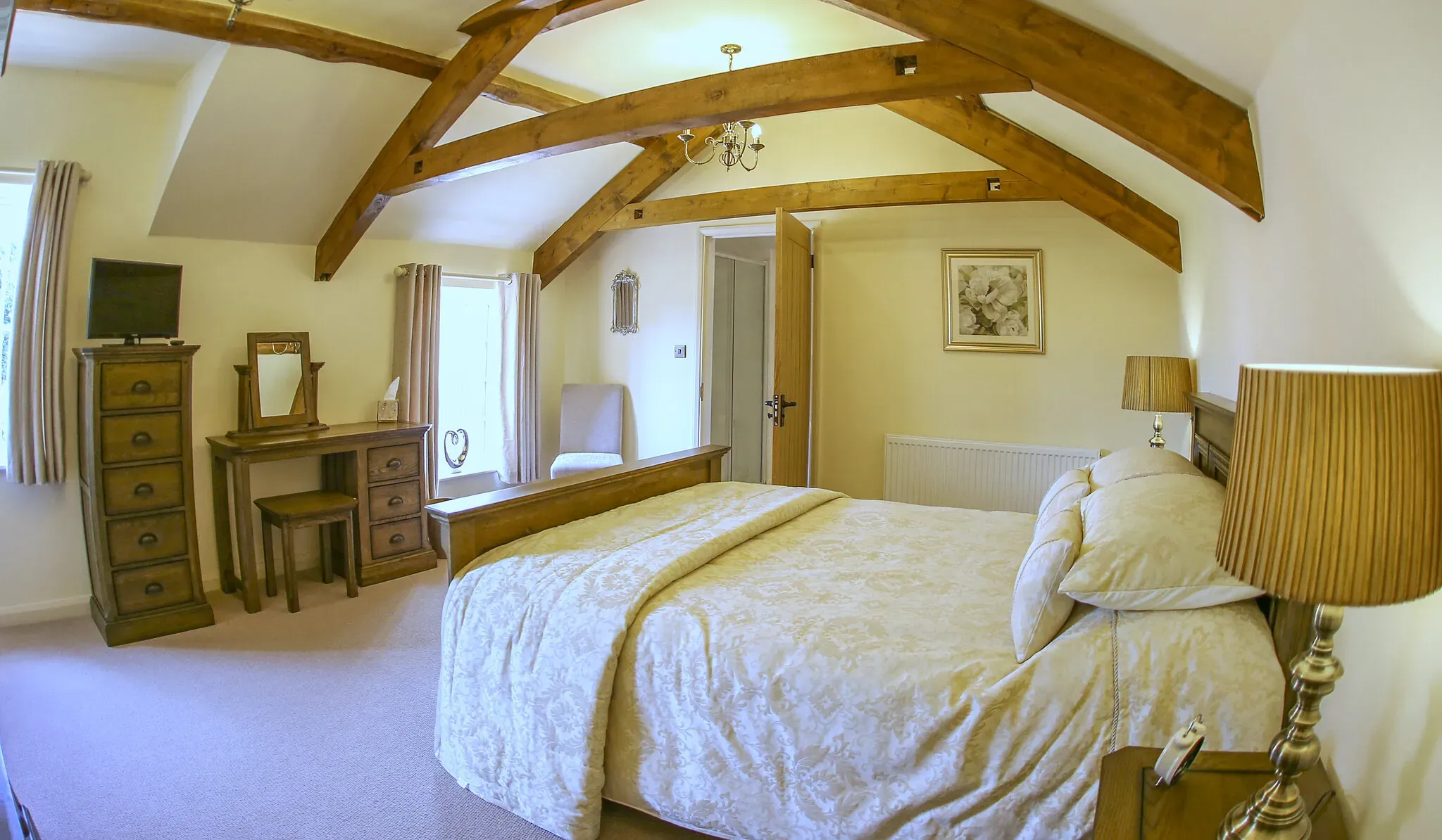 Oak Barn master bedroom with kingsize bed under exposed oak roof beams